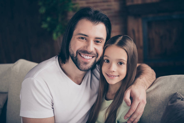 Photo of beautiful little adorable lady her handsome young daddy sit comfy sofa hugging dreamy smile spend weekend time homey domestic house room indoors - Photo, image
