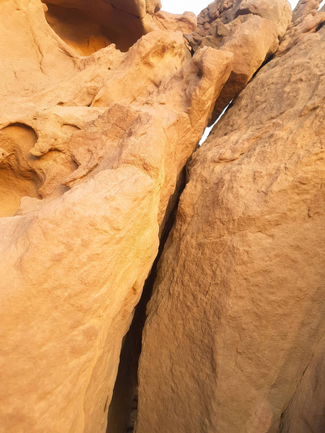 riesiger Sandsteinfelsen mit einem Riss in der Mitte. gelbe Kalksteinklippen, die auseinandergebrochen sind. Sandsteinmauer Hintergrund.  - Foto, Bild