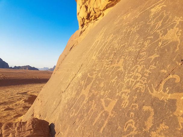 Sandsteinfelsen mit prähistorischer Kunst. Die prähistorische Zivilisation hinterließ ihre primitiven Zeichnungen auf einer Kalksteinklippe in der Wadi-Rum-Wüste in Jordanien. Steinzeitmalerei.  - Foto, Bild