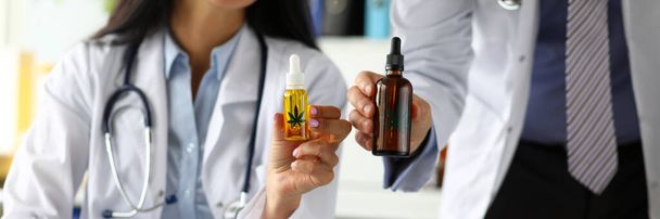 Two GP holding in hands jars of cannabinoid oil - Foto, imagen
