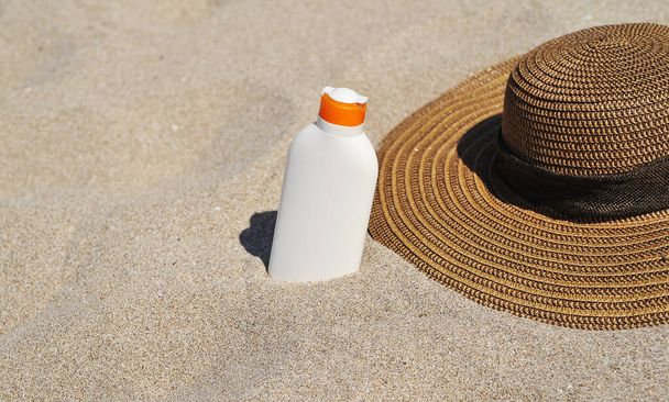Καπέλο και αντηλιακή προστασία στην άμμο, έννοια θερινή ώρα. - Φωτογραφία, εικόνα