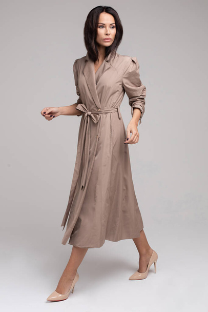 Pretty young lady in elegant trench coat walking in studio - Photo, Image