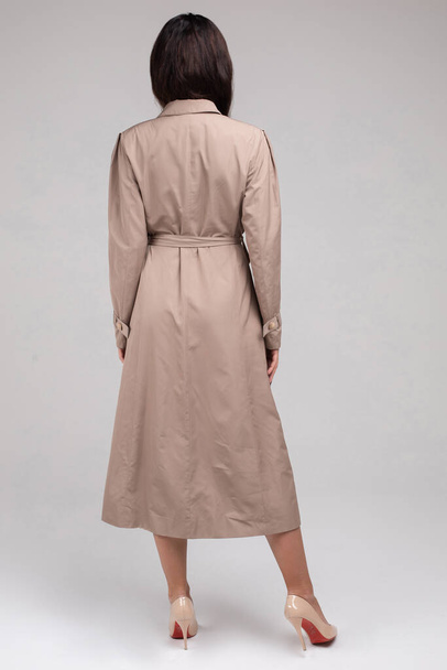 Beautiful woman in trench coat posing in studio - Фото, зображення