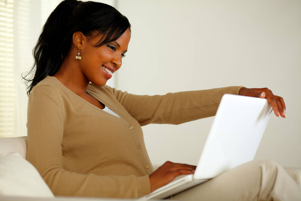 Portrait of a lovely black woman smiling and looking to laptop screen - Foto, Bild