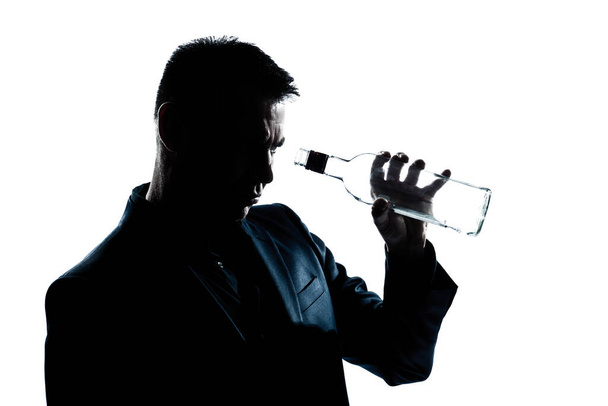 one caucasian man portrait silhouette drunk looking at an empty alcohol botlle in studio isolated white background - 写真・画像