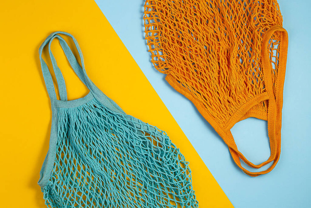 Zero waste concept. Two mesh shopping bags lie on yellow blue background - Foto, afbeelding