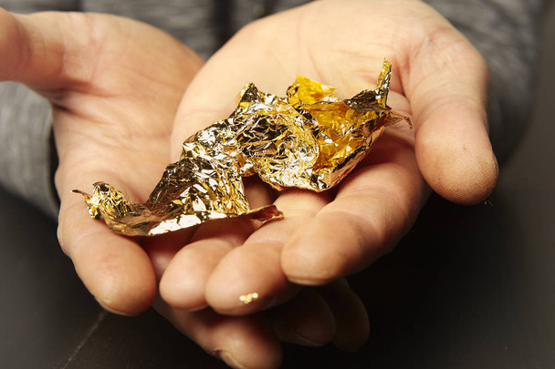 Artwork of gilding - sheet of creased gold metal plate in hands - Zdjęcie, obraz