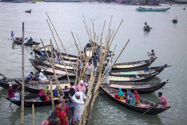 Personas que suben y bajan de un barco de madera en el puesto de botes en el río Turag para cruzar el río en sadarghat dhaka Bangladesh y anclaje de botes y salir de la terminal del barco
 - Foto, Imagen