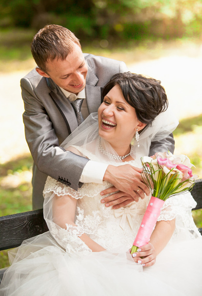 married couple laughing in park while sitting on bench - Photo, Image