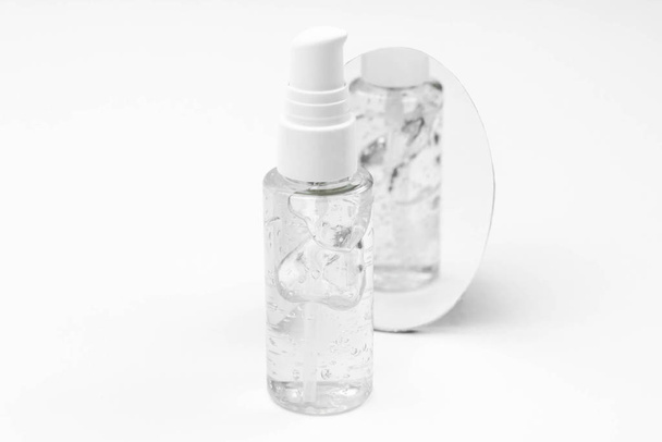 Cosmetic bottle with serum, gel, face cream on a white background with reflection in the mirror. Skin cosmetics, minimalism - Fotoğraf, Görsel