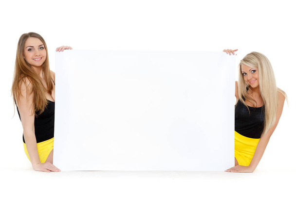 Two young pretty women with empty board for the text on a white background. - 写真・画像