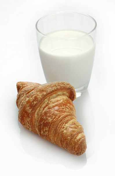 Studio shot of a glass of fresh milk and a croissant on a white background - Foto, afbeelding