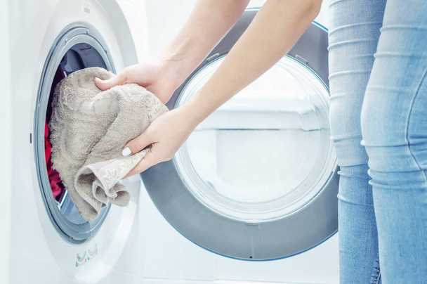 As mãos das mulheres põem a lavandaria na máquina de lavar roupa. Dama de casa. Fecha. Foco seletivo. Grãos de película
 - Foto, Imagem