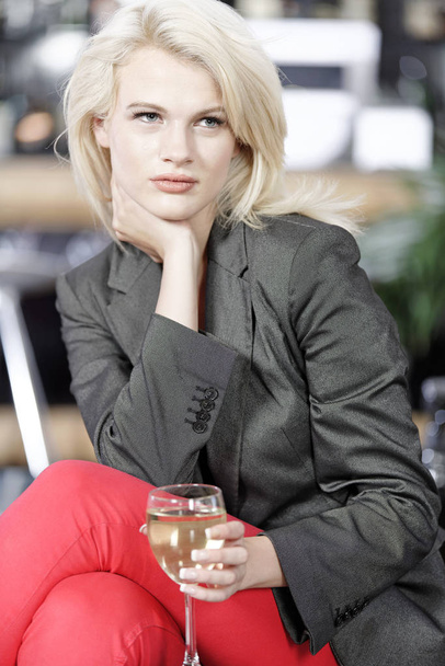 Attractive young woman enjoying a glass of white wine in a wine bar. - Foto, Imagem