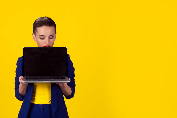 look here. Closeup portrait curious serious businesswoman corporate employee holding computer looking at screen peering peeking isolated yellow background office wall. Positive emotion face expression - Фото, зображення