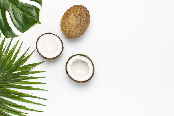 Tropical leaves and fresh coconut on light gray background top view copy space. Summer Flat lay background. Healthy cooking. Creative healthy food concept, half of coconut, nature - Фото, зображення