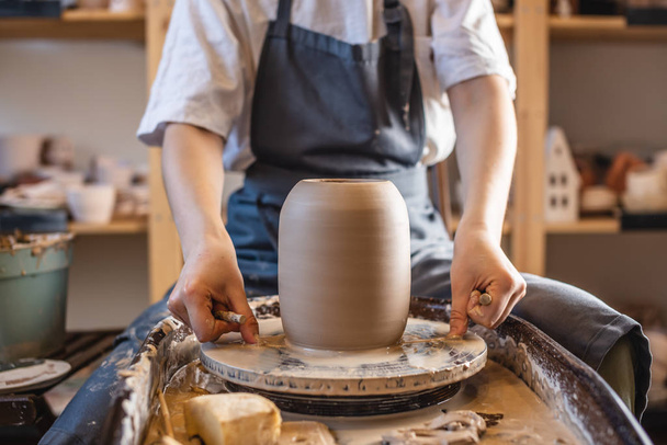Žena hrnčíř pracuje na hrnčířském kole dělat vázu. Mistr odtáhne džbán z kruhu a jemně ho drží v rukou. - Fotografie, Obrázek