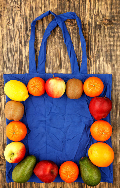 Sac en coton écologique de couleur bleue classique avec des fruits sur un fond en bois
. - Photo, image