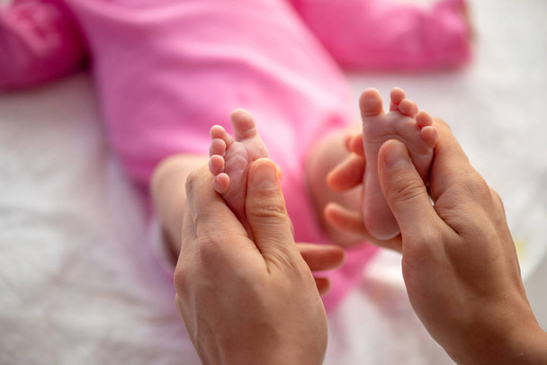 Matka lub lekarz masujący małą stopę dziecka - Zdjęcie, obraz