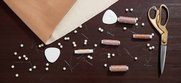 Grupo de objetos de costura acostado sobre una mesa de madera, concepto de sastrería
 - Foto, Imagen