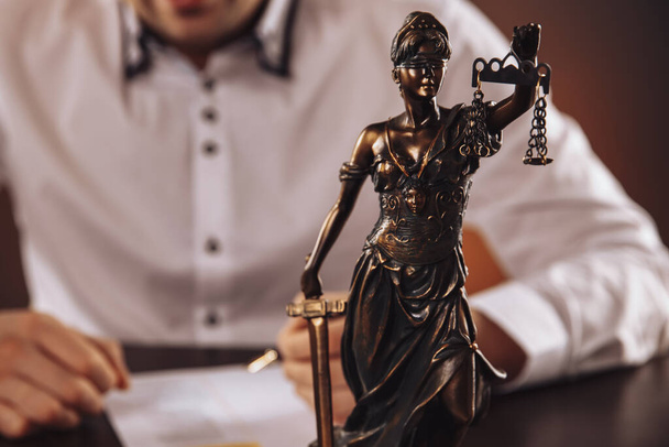 Closeup view of Statue Of Justice. Man in the white shurt on the background. - Photo, Image