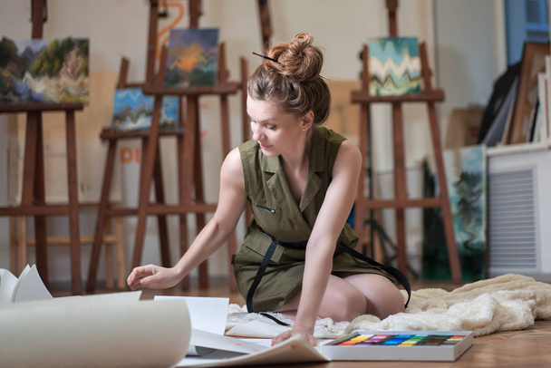 Portré egy női művész zsírkréta festmény, miközben ül a padlón a művészeti stúdió. - Fotó, kép