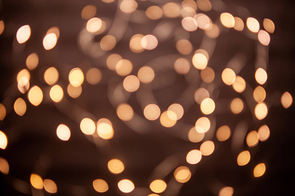 The background is a golden bokeh of the glare of garland lights. Defocus - Фото, изображение