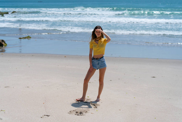 Houkutteleva pitkä tyttö seisoo rannalla rennosti käsin ylös shi
 - Valokuva, kuva