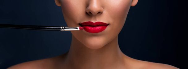Close up of red mat lips with cosmetic brush. Professional makeup. Banner. - Photo, Image