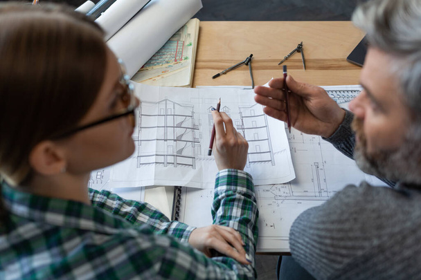 Interior designers team working in office with blueprints and architect equipment, sketching, negotiating and planning construction project. Partners discussing at work. Business construction concept - 写真・画像
