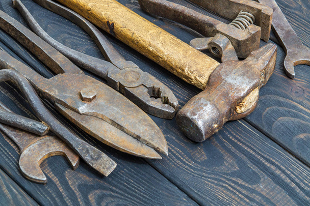 Old tools stacked after work on black vintage wooden boards - Zdjęcie, obraz