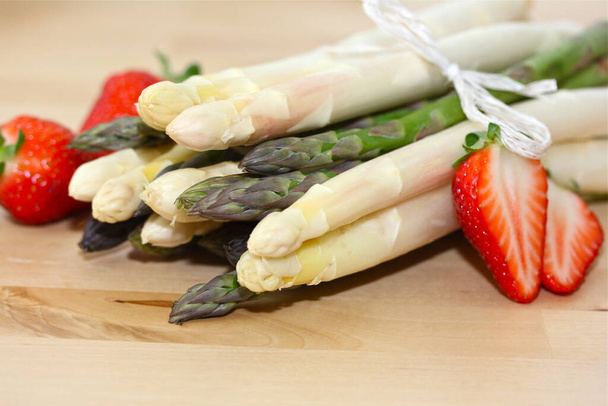 asparagus with strawberries on wooden table - Photo, image
