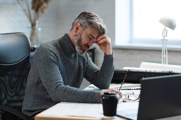 Tired architect working overtime in office. Stressed businessman have financial problems and searching ideas to overcome financial crisis. Entrepreneur in bankruptcy. Burnout and overwork concept - 写真・画像