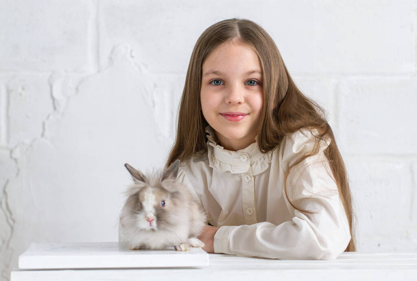 schattig klein meisje met konijn in de kamer - Foto, afbeelding