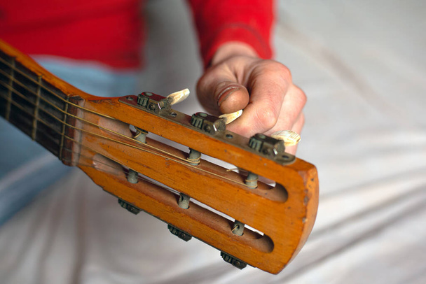 afinando a guitarra, o músico mão torce as melodias da guitarra, afinando o instrumento
 - Foto, Imagem