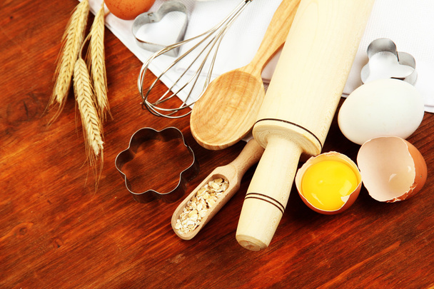 Cooking concept. Basic baking ingredients and kitchen tools on wooden table - Фото, изображение