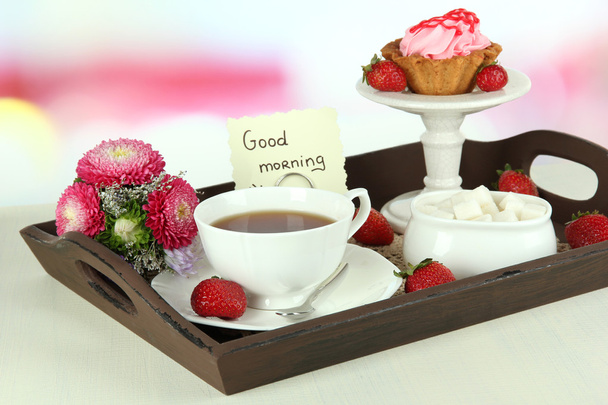 Cup of tea with cakes on wooden tray on table in room - Foto, afbeelding