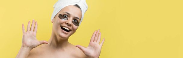 Menina bonita nova em uma toalha branca em sua cabeça usa manchas de gel de colágeno sob seus olhos. Máscara abaixo de cara de tratamento de olhos
. - Foto, Imagem
