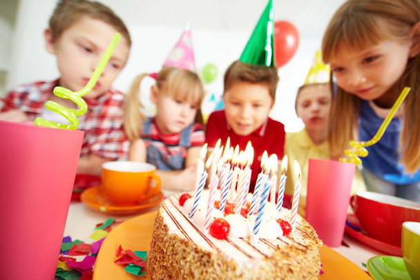 Group of adorable kids looking at birthday cake with candles - Foto, afbeelding