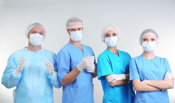Surgeons standing on grey background - Foto, imagen