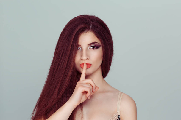 Hush. Young woman smiling asking for silence or secrecy with finger on lips shh hand gesture light green. Young woman with dark long hair keeping her forefinger by lips - Foto, Imagem