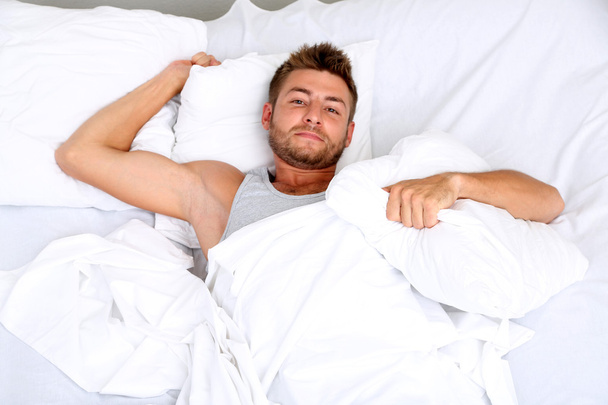 Handsome young man in bed - 写真・画像