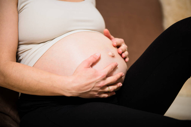 Detail of hands holding pregnant belly - indoors - Foto, Imagem