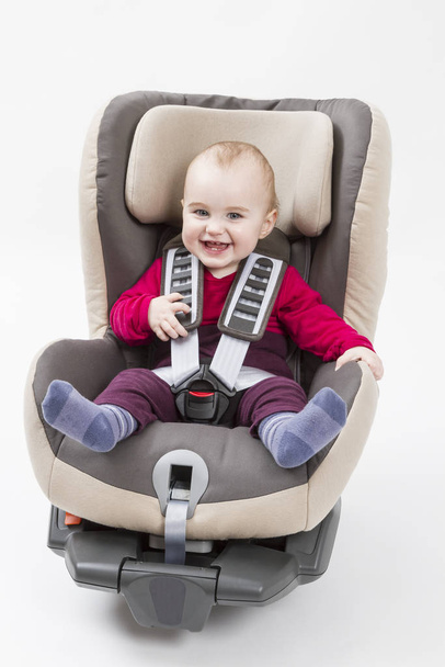 laughing child in booster seat for a car in light background. - 写真・画像