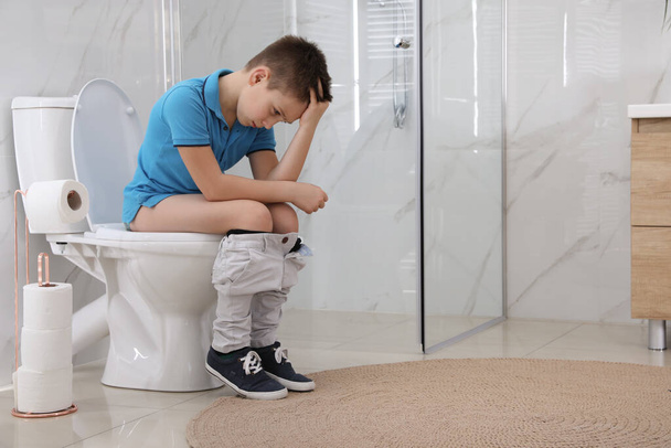 Boy suffering from hemorrhoid on toilet bowl in rest room - Foto, Bild