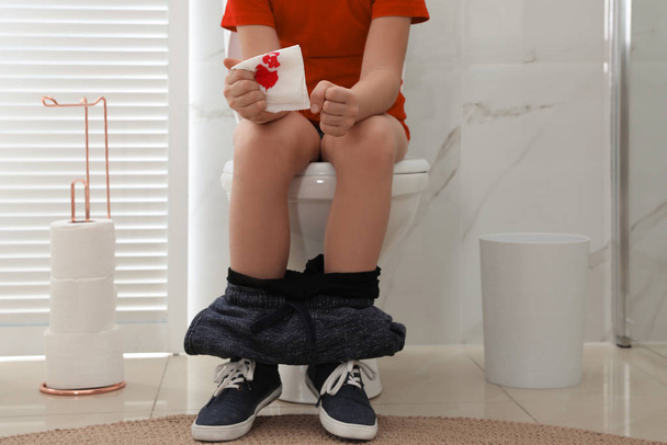 Boy holding toilet paper with blood stain in rest room, closeup. Hemorrhoid concept - Valokuva, kuva