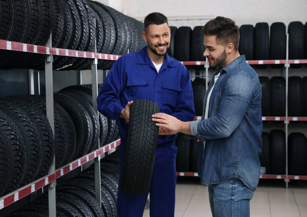 Mechanic helping client to choose car tire in auto store - Photo, image