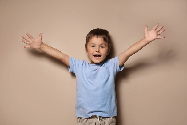 Portrait of happy little boy on beige background - Φωτογραφία, εικόνα