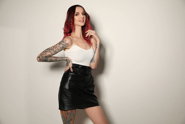 Beautiful woman with tattoos on body against light background - Фото, изображение