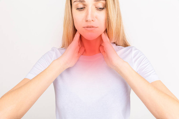 Female checking thyroid gland by herself. Close up of woman in white t- shirt touching neck with red spot. Thyroid disorder includes goiter, hyperthyroid, hypothyroid, tumor or cancer. Health care. - Photo, Image